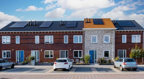 Straat met huizen met zonnepanelen op het dak en een elektrische auto aan de straat geparkeerd